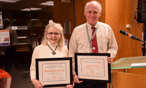 two people standing side by side holding plaques