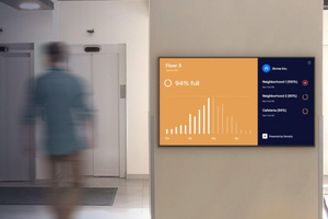 person walking next to a wall monitor