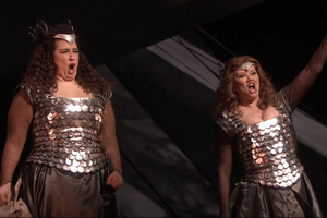 two opera singers in ornate bronze-colored dresses