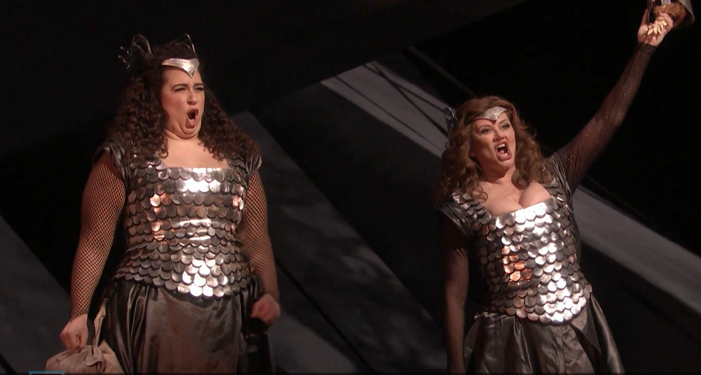 two opera singers in ornate bronze-colored dresses