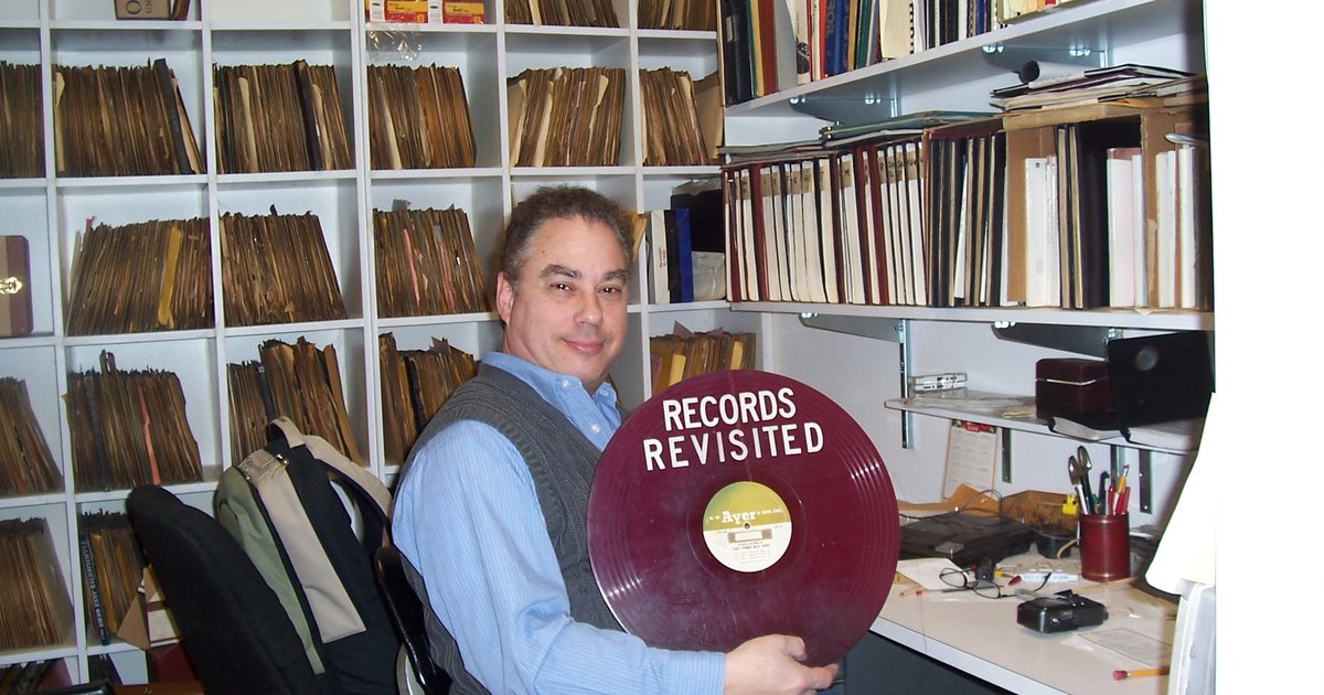 Eli Savada with a record in front of wall of records