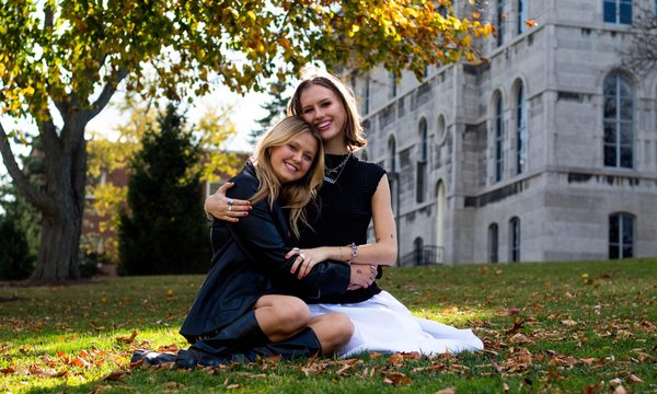Emma Lueders and Jennie Bull hug for a photo in front of Hall of Languages