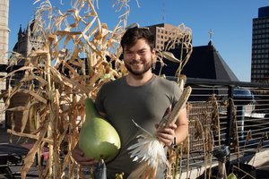 Ethan holds some of his harvest, including corn from The AlterNative Project