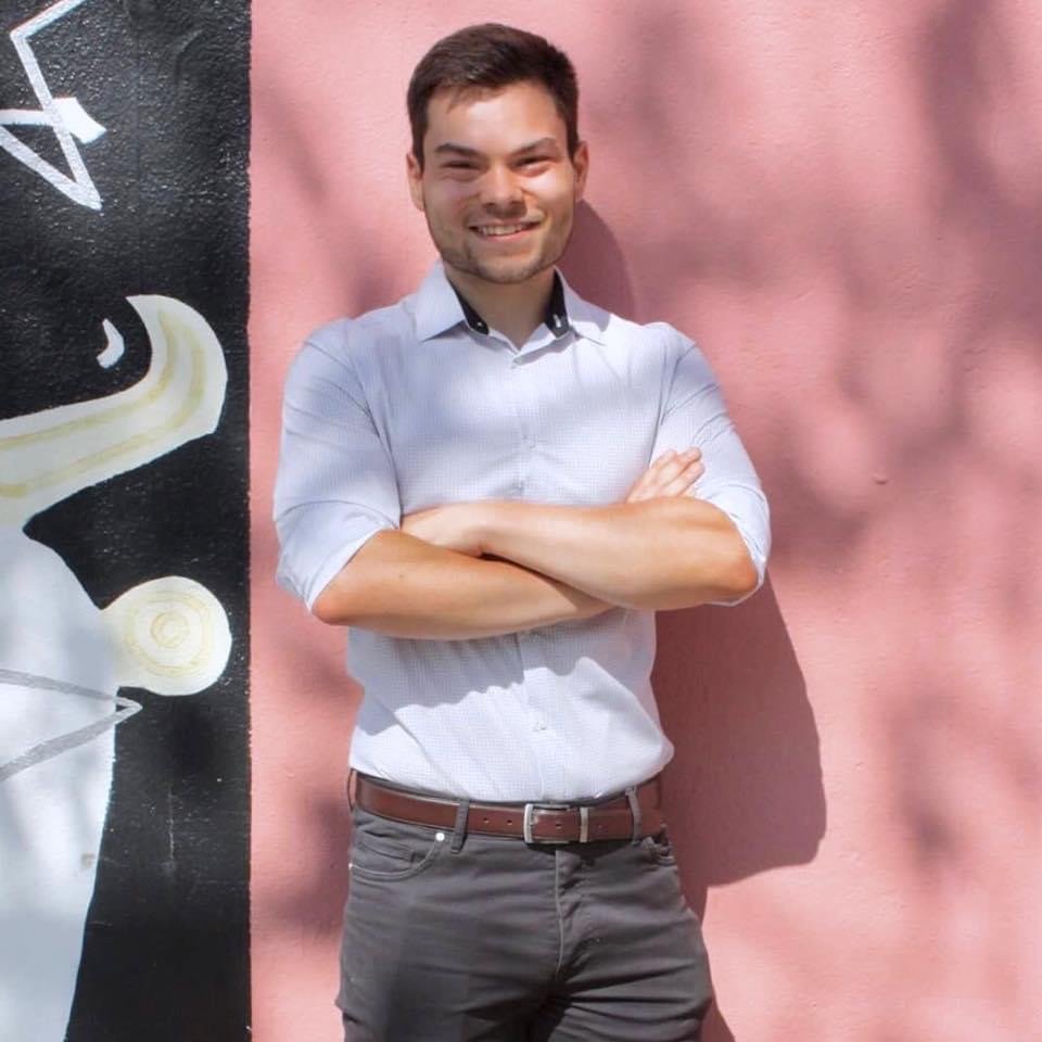 Ethan Tyo poses for a photo in front of a pink wall