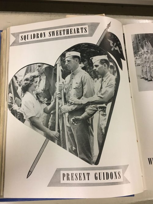 Black and white page with a heart-shaped image of a woman and multiple men in uniform holding flags.