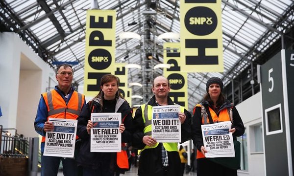 four people standing side by side holding up newspapers with different titles