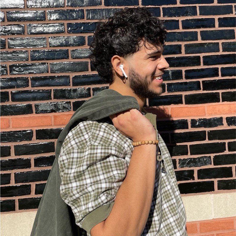 Gabriel Davila-Campos smiling, looking to the right side, while holding a sweater over his shoulder