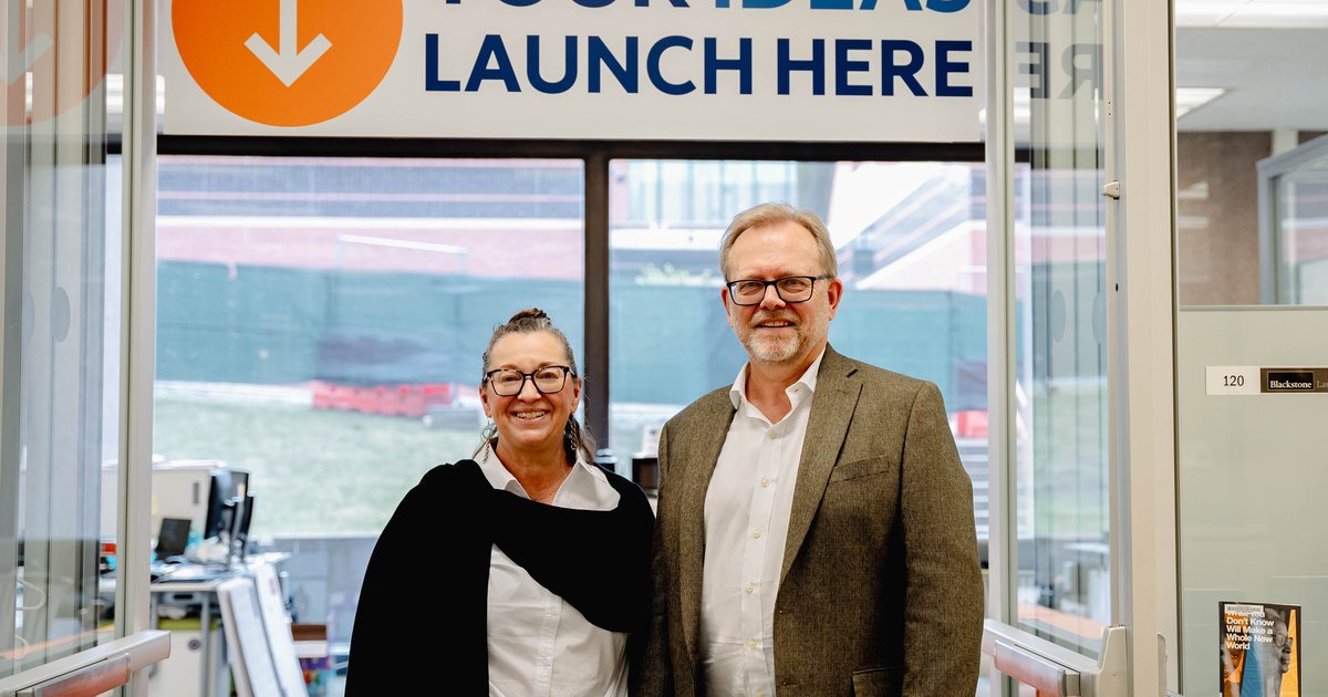 female and male standing in doorway below sign that reads "your ideas launch here"