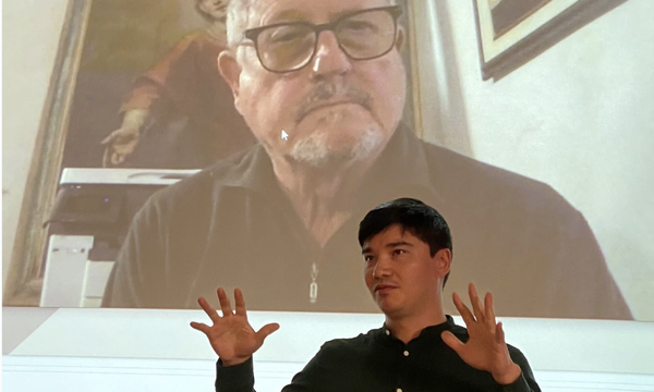 person on screen behind person standing in front of screen