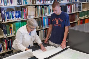 Library staff person helps student with government documents and maps collection.