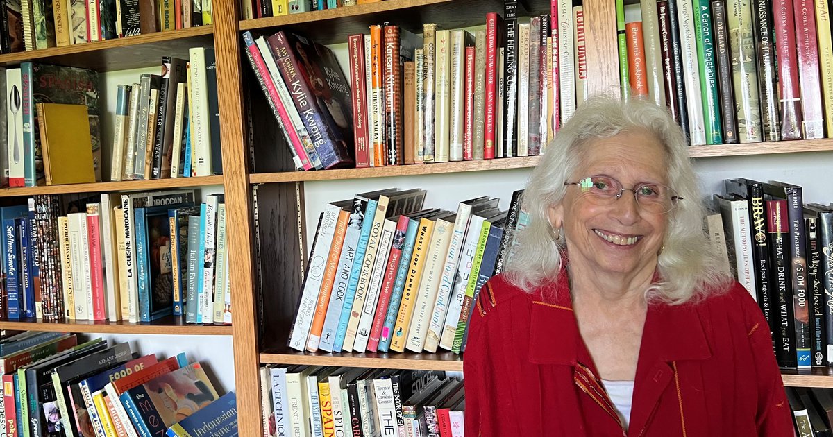 person with red top sits in front of bookcase