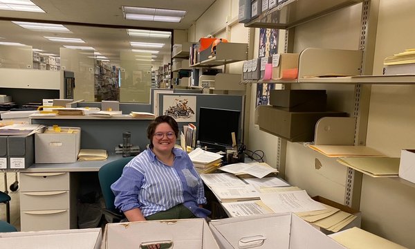 person sitting amongst boxes and papers in office
