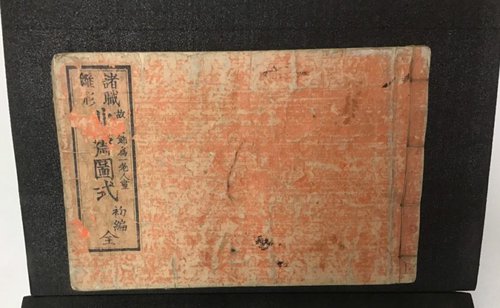 Red and tan book cover with Japanese characters on the left side surrounded by a box.