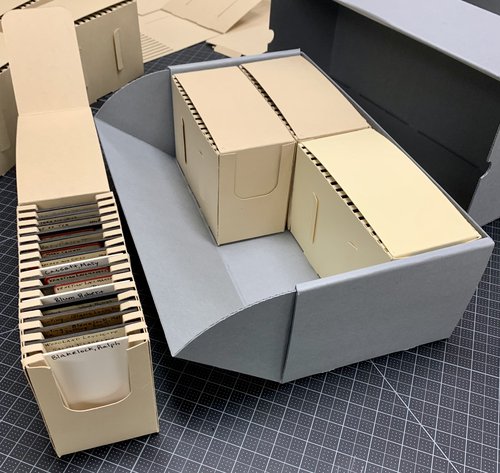 beige box that holds each glass plate negative next to larger gray box that holds three beige boxes