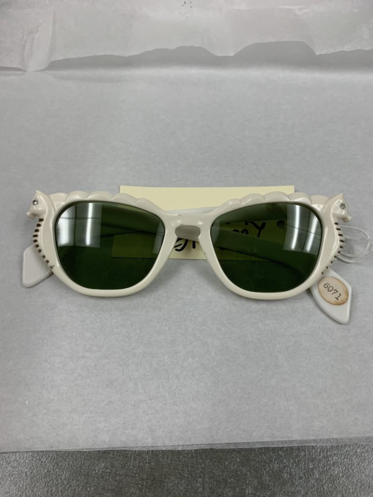 Pair of white sunglasses with seahorses on the sides of the lenses.