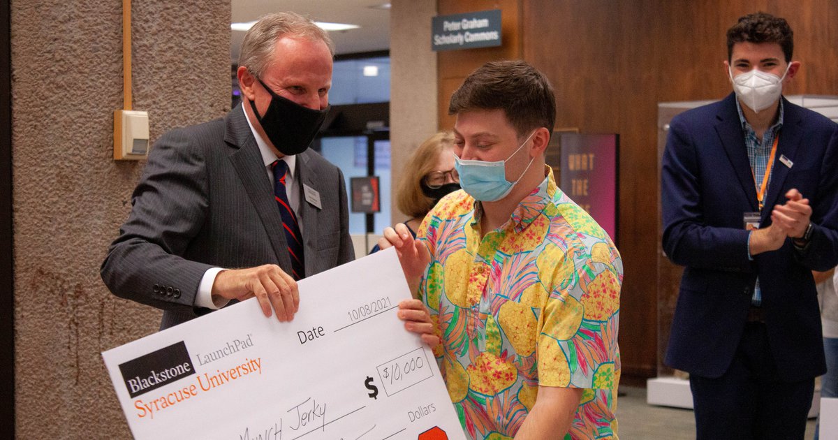 Libraries dean David Seaman handing student a $10,000 addressed to startup Munch Jerky