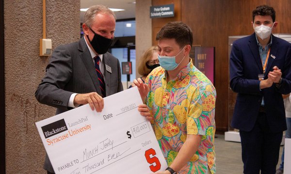 Libraries dean David Seaman handing student a $10,000 addressed to startup Munch Jerky