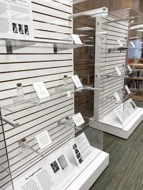 two display cases with various glass bottles on display and descriptions next to each