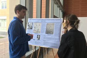 man standing next to poster while discussing it with another person