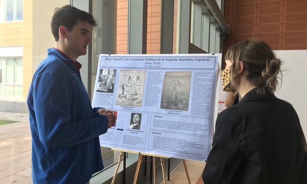 man standing next to poster while discussing it with another person