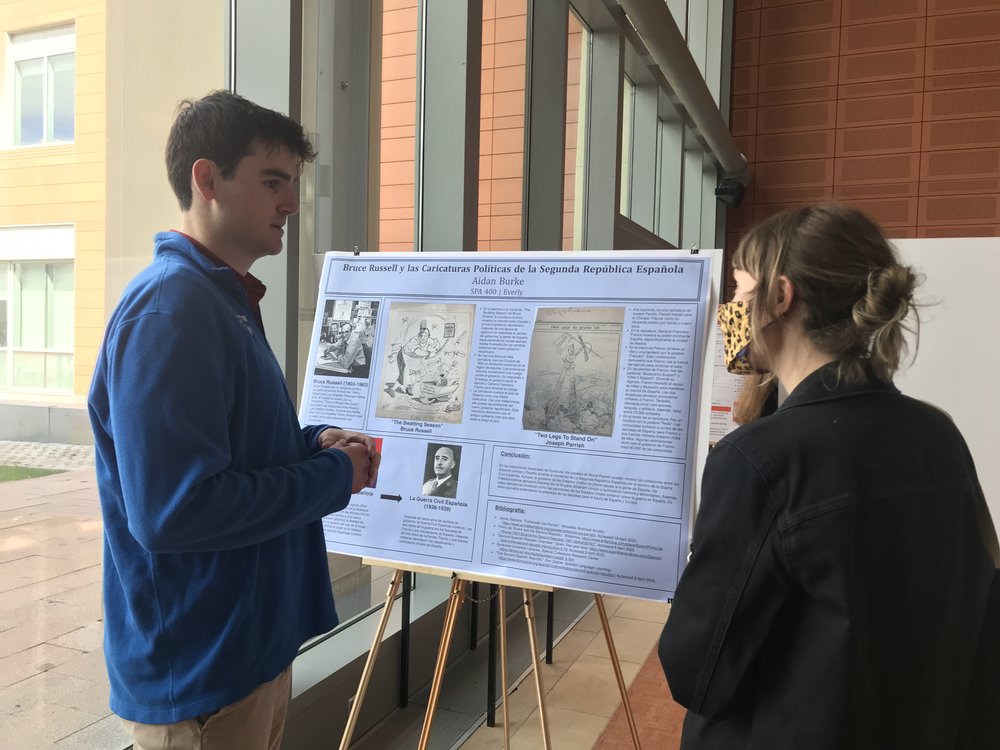 man standing next to poster while discussing it with another person