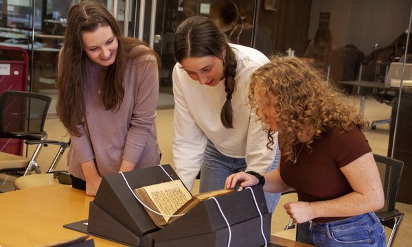 3 people looking at rare book