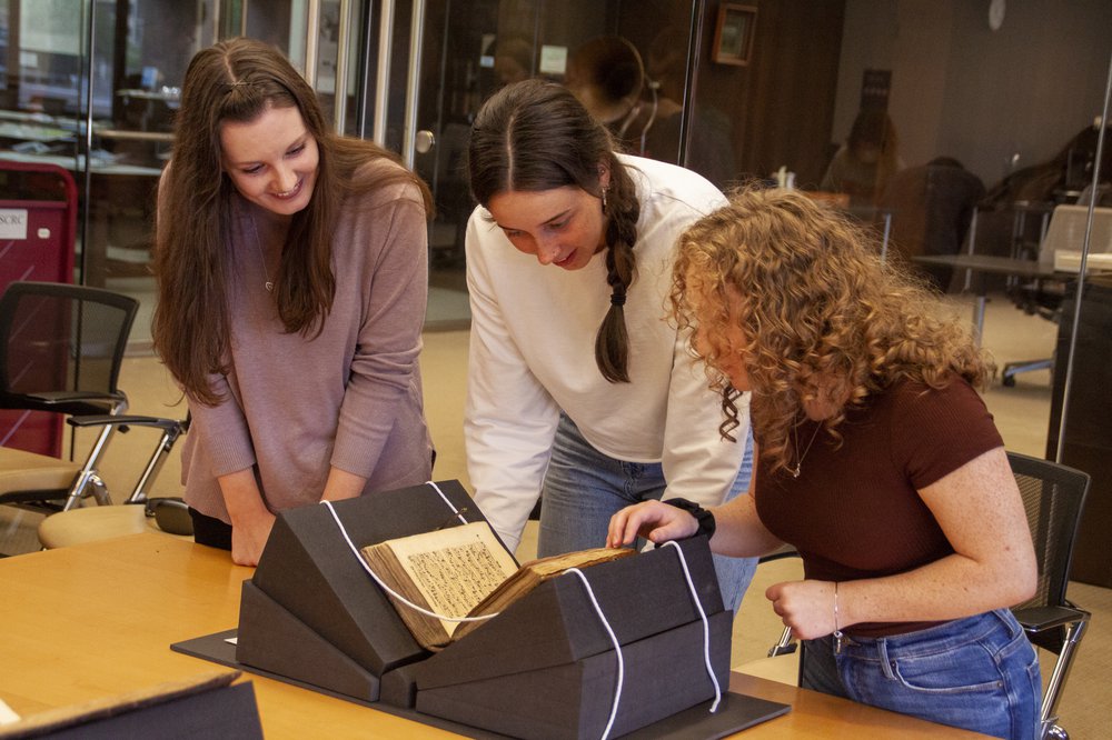 3 people looking at rare book