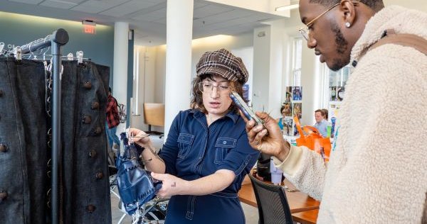 person showing clothing on rack to another person