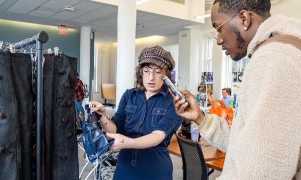 person showing clothing on rack to another person