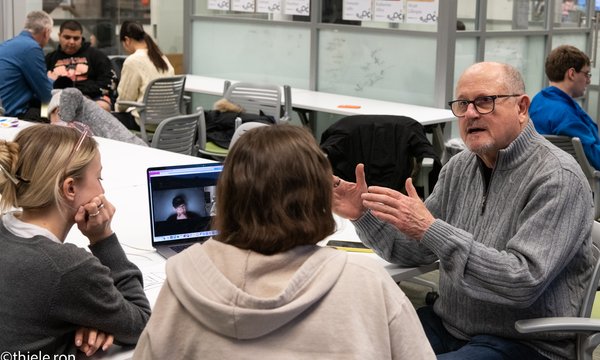 person sitting at table talking to students
