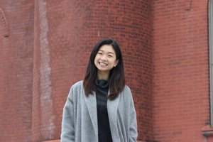 student standing in front of brick campus building
