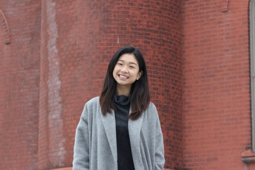 student standing in front of brick campus building