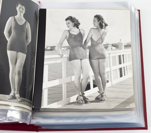 Models wearing swimsuits leaning on a railing