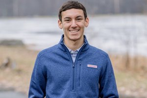 young man standing outside in front of pond