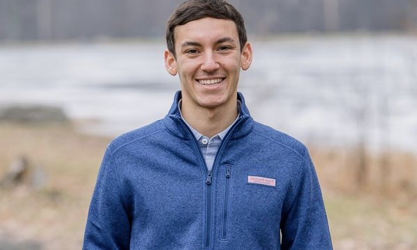 young man standing outside in front of pond