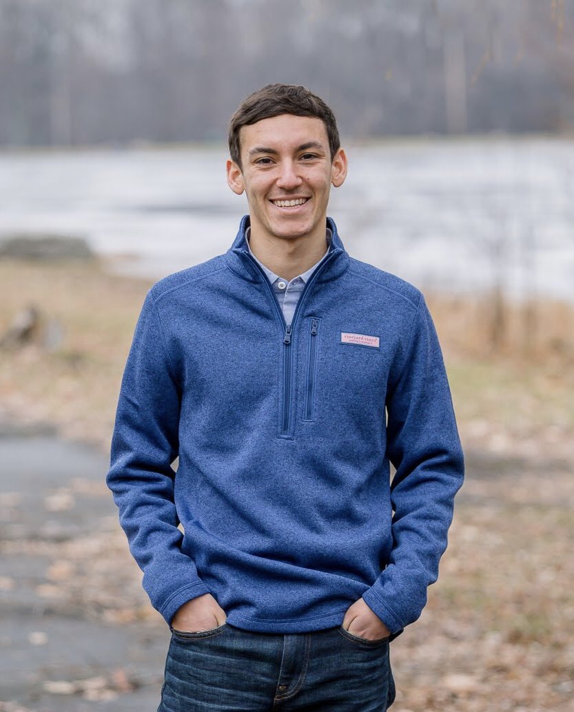 young man standing outside in front of pond