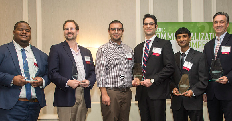 Six men in professional attire, each holding an award