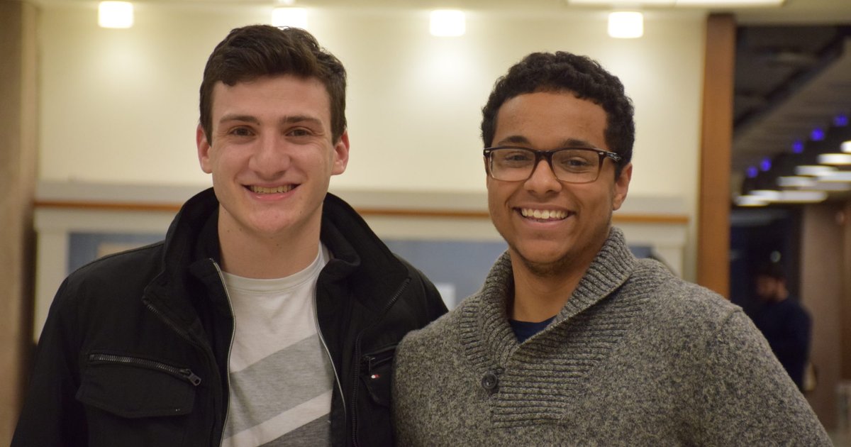 Two students smile for a photo in the library