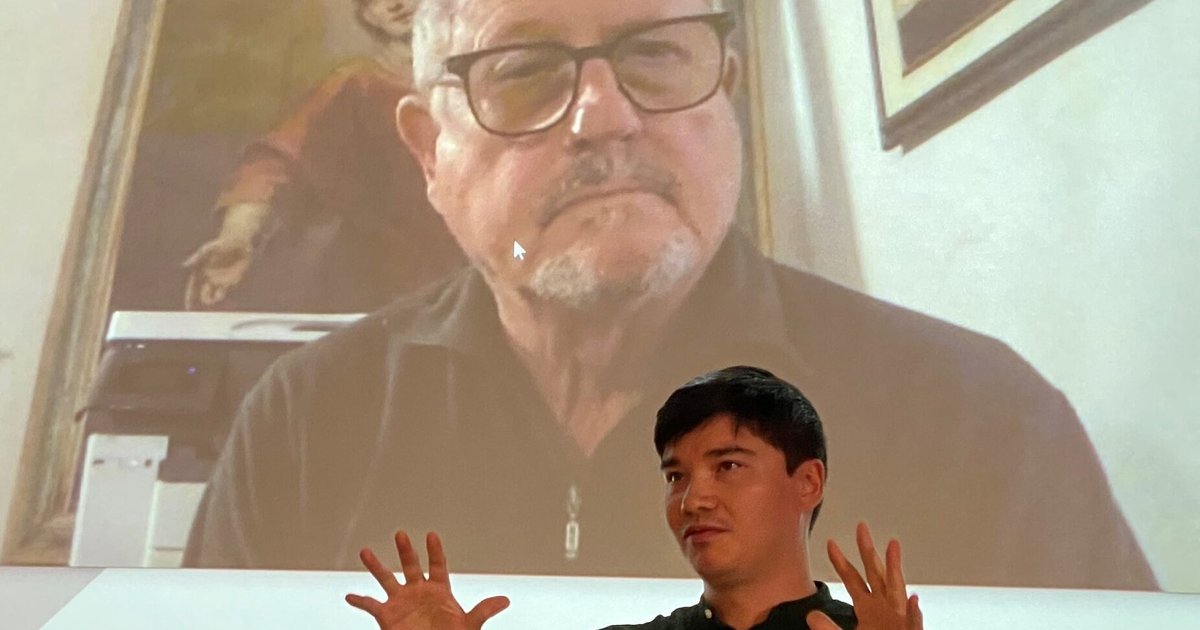 Kai Patricio in black flannel shirt speaks in front of Gianfranco Zaccai over zoom