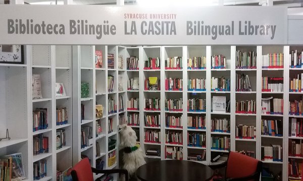 books on shelves with sign that reads Syracuse University Biblioteca Bilinguie La Casita Bilingual Library