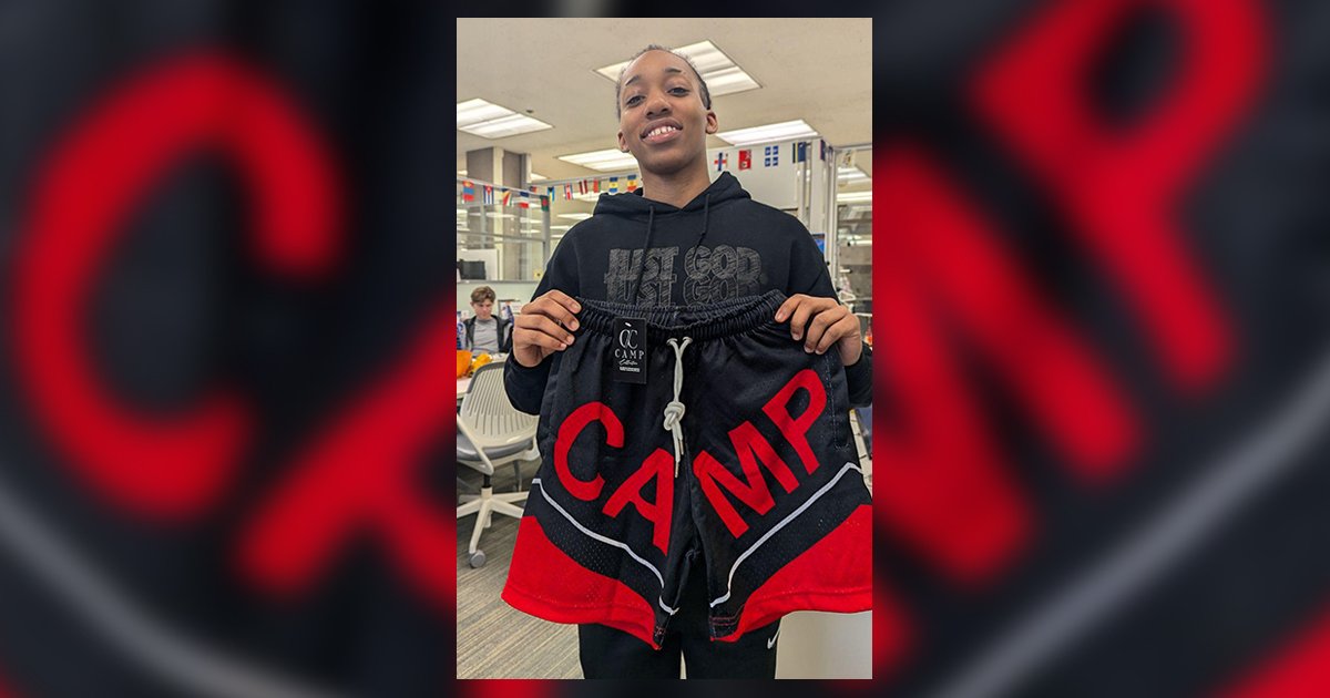 person holding up gym shorts with word CAMP on shorts