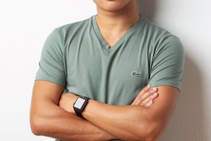 man leaning against a white wall with his arms crossed