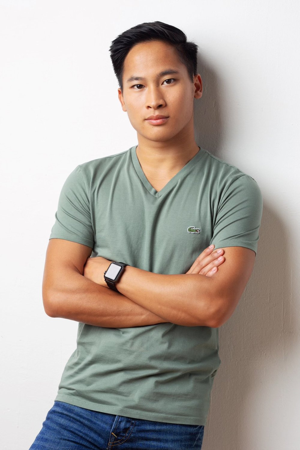 man leaning against a white wall with his arms crossed