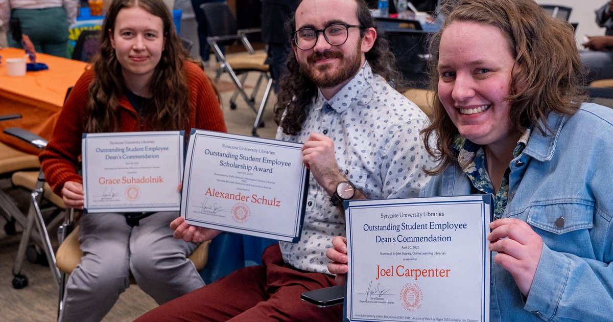 three people holding awards