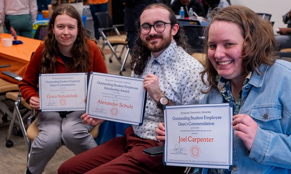 three people holding awards