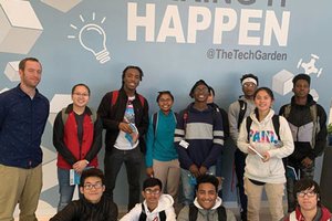 group of young p-tech students posing under wall that reads "Making it Happen"
