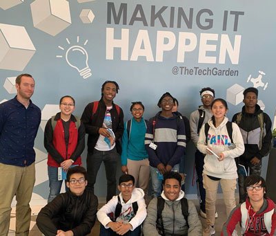 group of young p-tech students posing under wall that reads "Making it Happen"