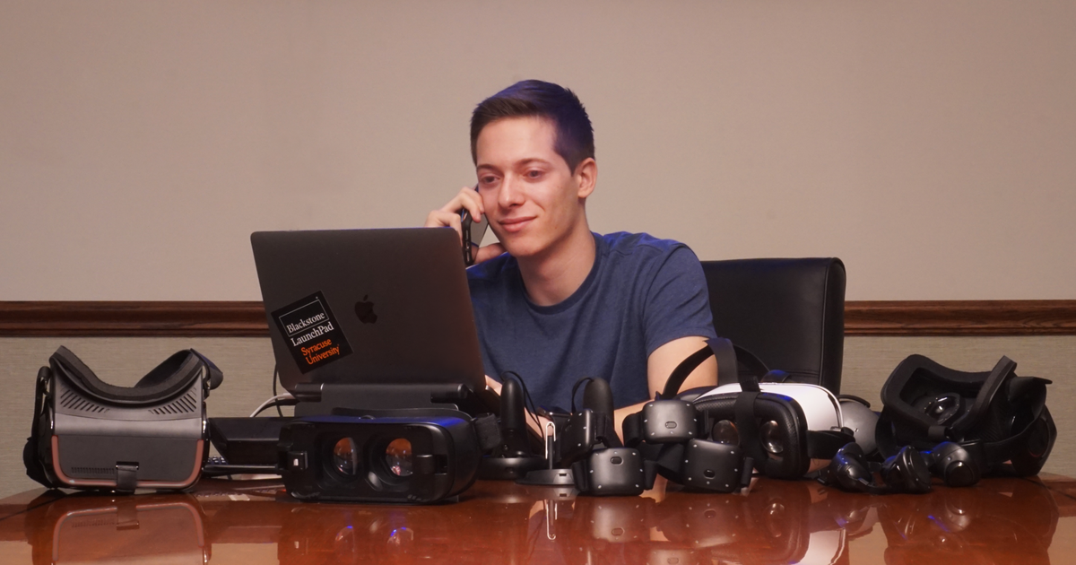 man on a photo sitting at the table filled with VR headsets