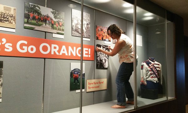 Meg Mason standing inside glass display case, assembling display