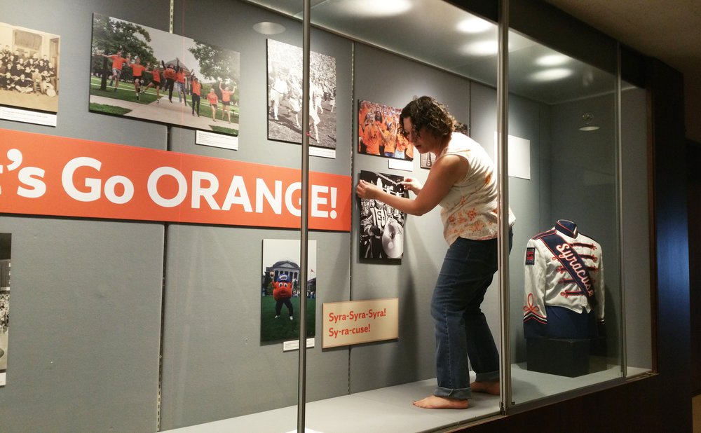 Meg Mason standing inside glass display case, assembling display